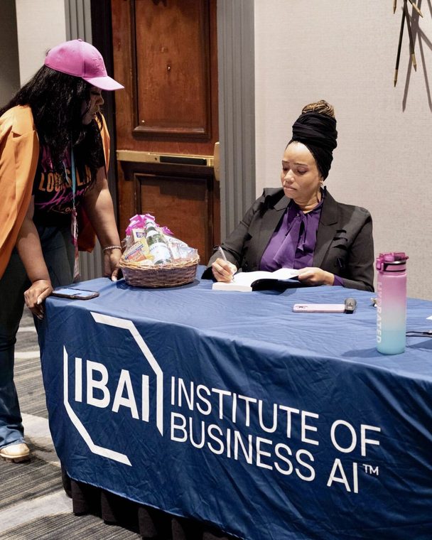 TerDawn DeBoe signing pre-sale copies at the Institute of Business AI table